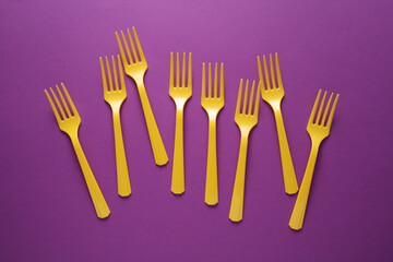 Yellow Plastic forks on purple background.