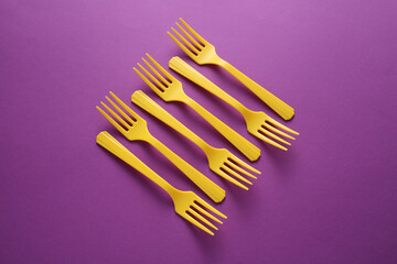 Yellow Plastic forks on purple background.