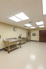 A sterile room with a stainless steel table, clock, and medical equipment.