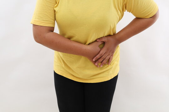 Asian woman's standing holding left stomach, suffering from stomach pain in the left side. Isolated on white