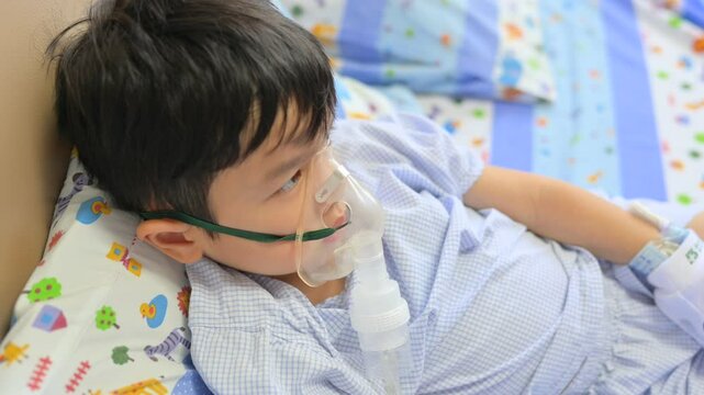 Boy 4 years old , inhale medication by inhalation mask to cure Respiratory Syncytial Virus (RSV) on hospital bed. Admitted patient boy inhalation therapy.