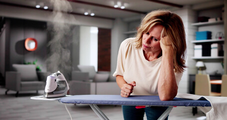 Unhappy Woman Leaning On Ironing Board Next To Piles