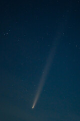 Vertical Comet tail in the sky, night landscape. Comet surrounded by stars in blue dark sky....