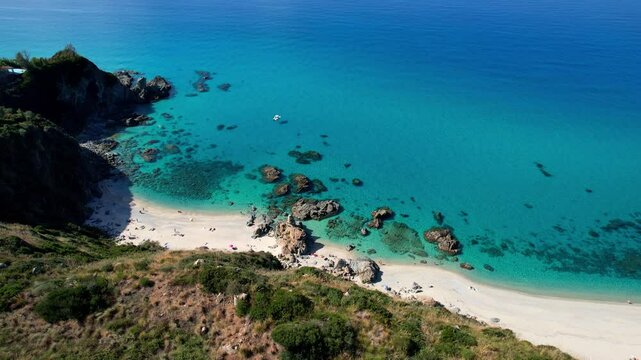 4K Aerial drone video of one of the most beautiful beaches in the world with turquoise clear blue water and white sand with big rocks on a sunny summer day. Marinella di Zambrone Paradiso Tropea Italy
