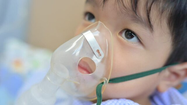Boy 4 years old , inhale medication by inhalation mask to cure Respiratory Syncytial Virus (RSV) on hospital bed. Admitted patient boy inhalation therapy.