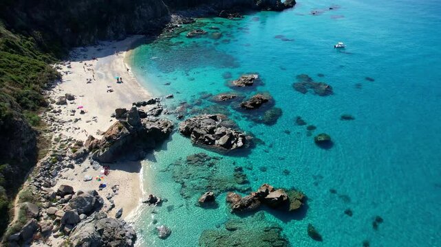 4K Aerial drone video of one of the most beautiful beaches in the world with turquoise clear blue water and white sand with big rocks on a sunny summer day. Marinella di Zambrone Paradiso Tropea Italy