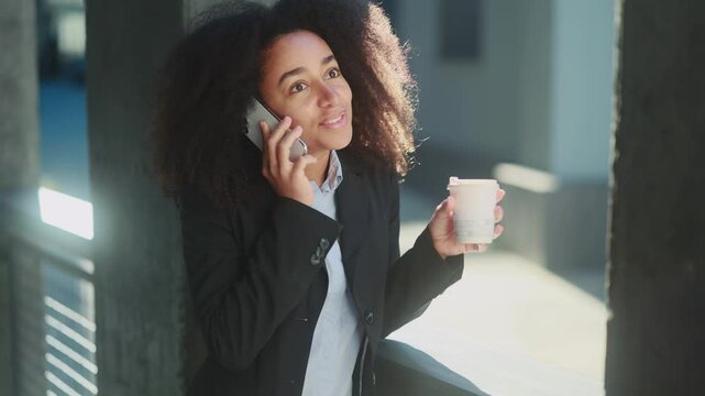 Successful confident businesswoman talking on mobile phone has working or personal conversation while has break at office centre Positive worker employee with cup of coffee using smartphone outdoors