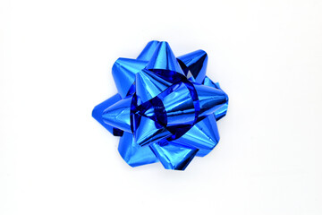 A shiny blue ribbon twisted into a star decoration lies on a white background.