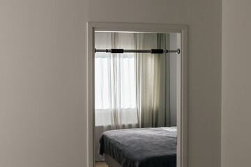 A pull-up bar is set up in the interior. In the background, there is a bedroom interior.