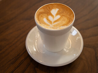Delicious coffee with milk in white cup on a brown textured table, closeup. 