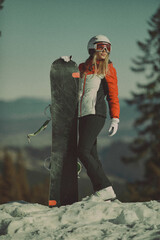  A girl with a snowboard in her hands against the backdrop of snowy mountains