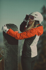  A girl with a snowboard in her hands against the backdrop of snowy mountains