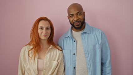 Interracial couple in love standing together against a pink background, showcasing a happy, affectionate relationship between a man and a woman