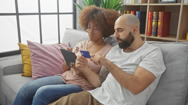 A multicultural couple shopping online with credit card and smartphone at home