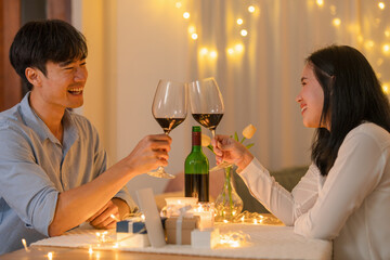 Lovely couple celebrating with red grape wine ,They sitting at the dinning table in cozy room at  home.