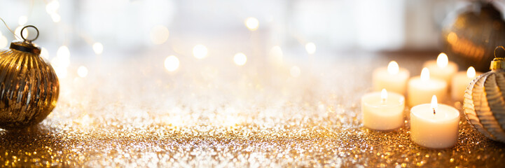 Christmas balls with candles surrounded by golden glittering confetti. Elegant horizontal...