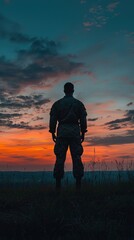 A soldier stands against a vibrant sunset, symbolizing strength and resilience in a serene landscape.