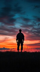 Fototapeta premium A silhouette of a soldier stands against a vibrant sunset, showcasing a blend of colors and evoking themes of bravery and solitude.