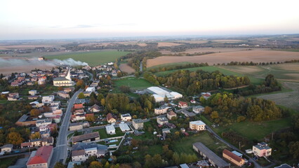 autumn background view of the village from a drone, smoke from a chimney and burning leaves