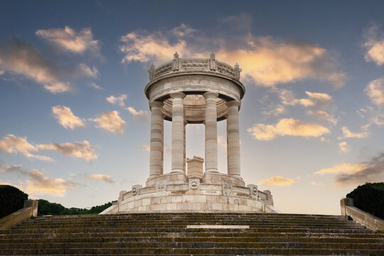 A colorful sunset photo features a stunning sky filled with vibrant hues, highlighting the Passetto monument as the focal point in the foreground. The scene beautifully captures the charm of Ancona. 