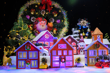A large Christmas town with a chapel and large decorated houses and cars near them against the...