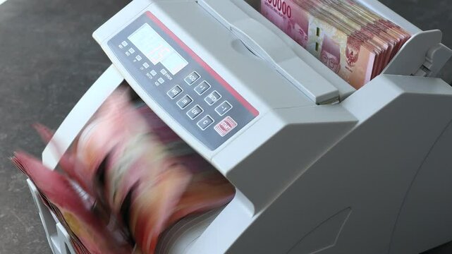 Counting Indonesian Rupiah in money converting machine. One hundred thousand rupiah banknotes. Financial concept. Indonesia money, close up