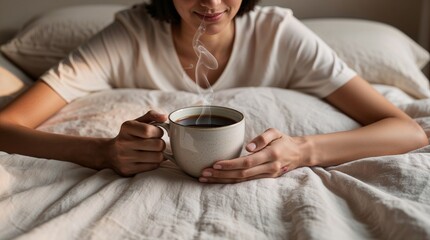 A person enjoys a peaceful morning, lying in bed with a warm cup of coffee. The cozy setting features soft white linens, inviting a sense of comfort and relaxation. 