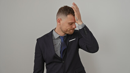 A young man in a suit appears stressed against a white background, displaying a universal expression of worry or mistake.