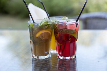 Three drinks with straws in them are on a table