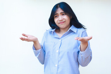 confused asian woman wearing casual stripes shirt pointing finger to empty space thinking choices standing over isolated white background