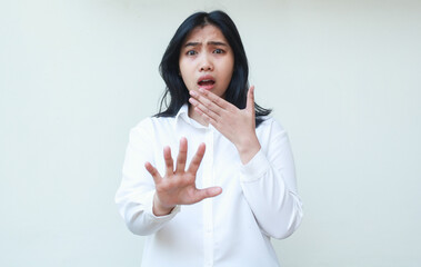 portrait of terrified shock asian business woman reaching hands towards camera and covering mouth looking at camera show frightened face expression wear white shirt formal suit standing isolated