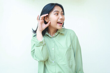 excited asian woman wearing green over size shirt do listening gesture, eavesdropping, looking away...