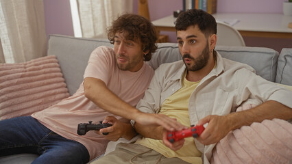 Men enjoying video games on a cozy sofa in a modern apartment living room, showcasing friendship and leisure time indoors.