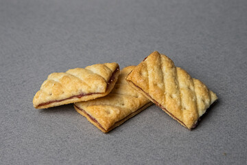 three rectangular cookies with filling stacked in a pile on a gray background