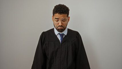 Young man in a black robe looking sad over isolated white background