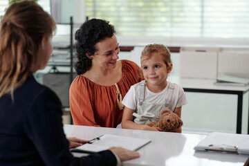 Woman with child talking to social worker during meeting in office