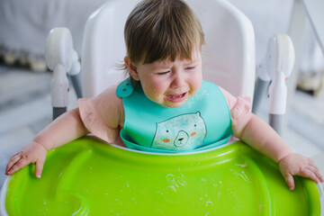 A small child is crying at the table. He doesn't want to eat