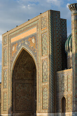 Portal and columns in Ulug Beg madrassa in the Registan of Samarkand with flower garden at sunset