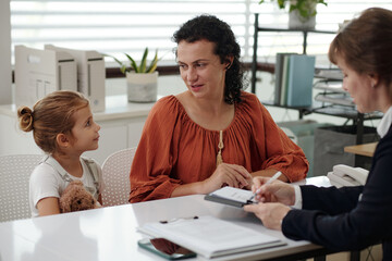 Single mother with her child talking to social worker in office
