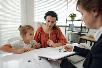 Social worker discussing adoption document with woman while they sitting at table with child