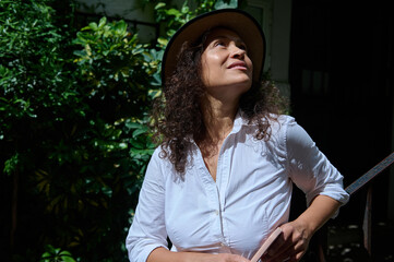 Woman in white shirt and hat enjoying a sunny day outdoors