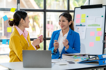 Collaborative Brainstorm:  Two professional women in a modern office setting engage in a lively conversation, exchanging ideas while working on a project. Their body language conveys enthusiasm.