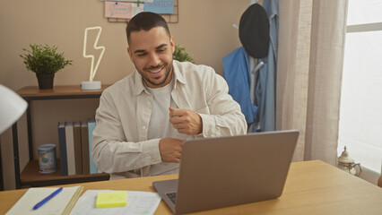 Smiling young hispanic man using laptop in a cozy home office setting