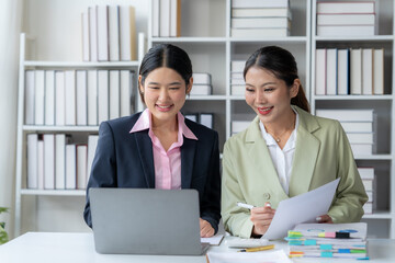 Collaborative Success: Two professional women, dressed in business attire, are engrossed in a...