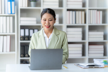 Focused and Productive: A young Asian businesswoman sits at her desk, deeply engrossed in her work...