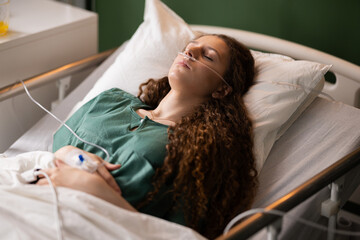 Red-haired girl, with a catheter and an oxygen tube, lies in bed, harmonizing strength and serenity...