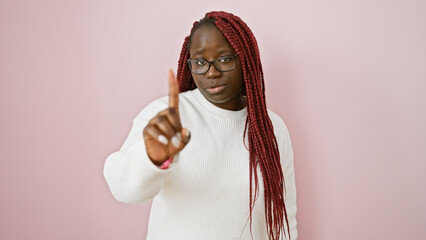 Adult black woman with braids gesturing no against a pink isolated background.