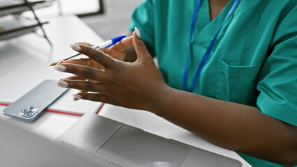 African american woman with braids wearing a clinic uniform working indoors at a rehab center.