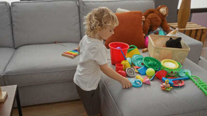 Toddler boy playing with colorful toys in a cozy home living room setting surrounded by stuffed animals and cushions
