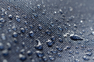 Rainwater drops on blue waterproof fabric, top view. Water drops on waterproof soaked fabric in the rain. Water drops on blue waterproof fabric.